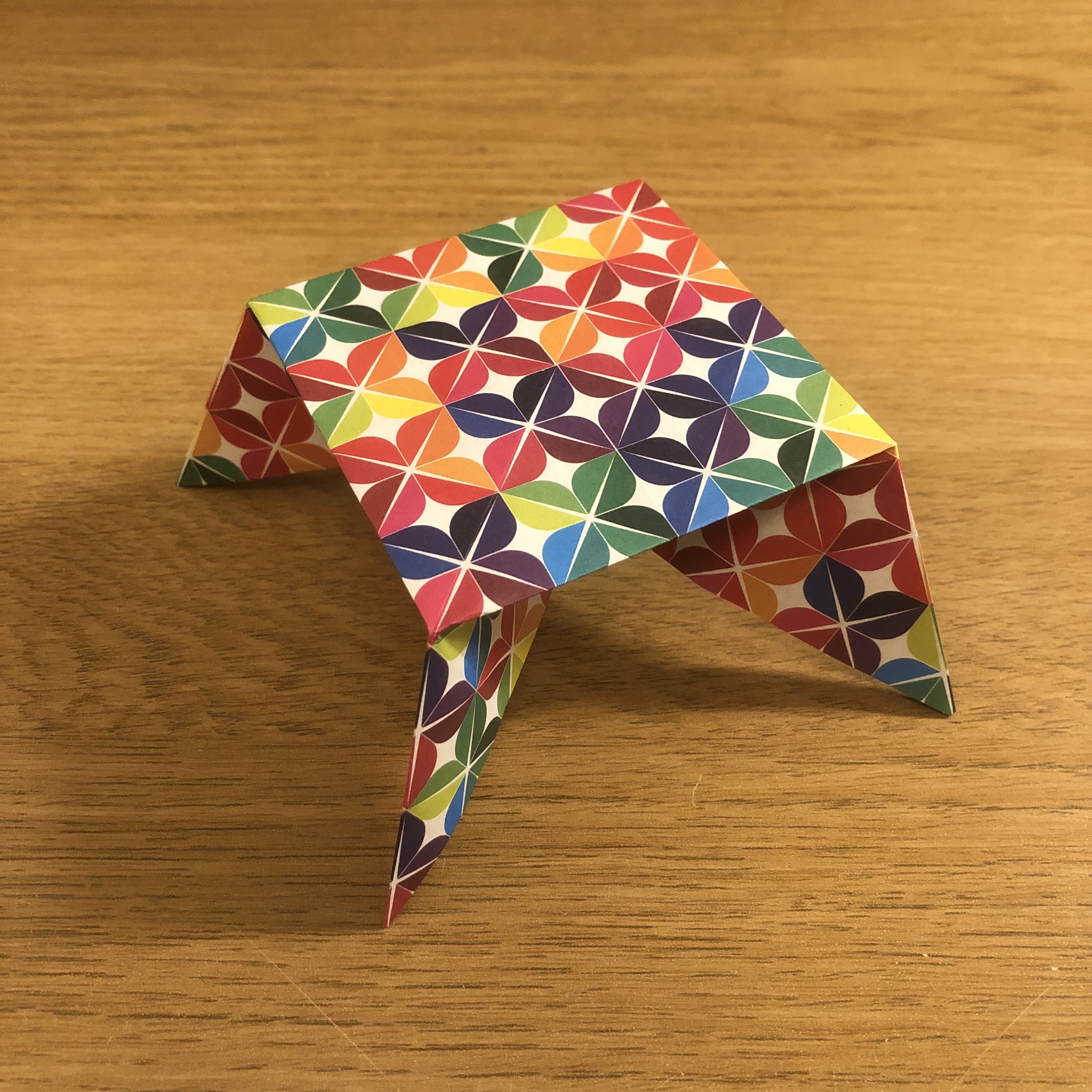 A colorful folded paper on a wood surface.