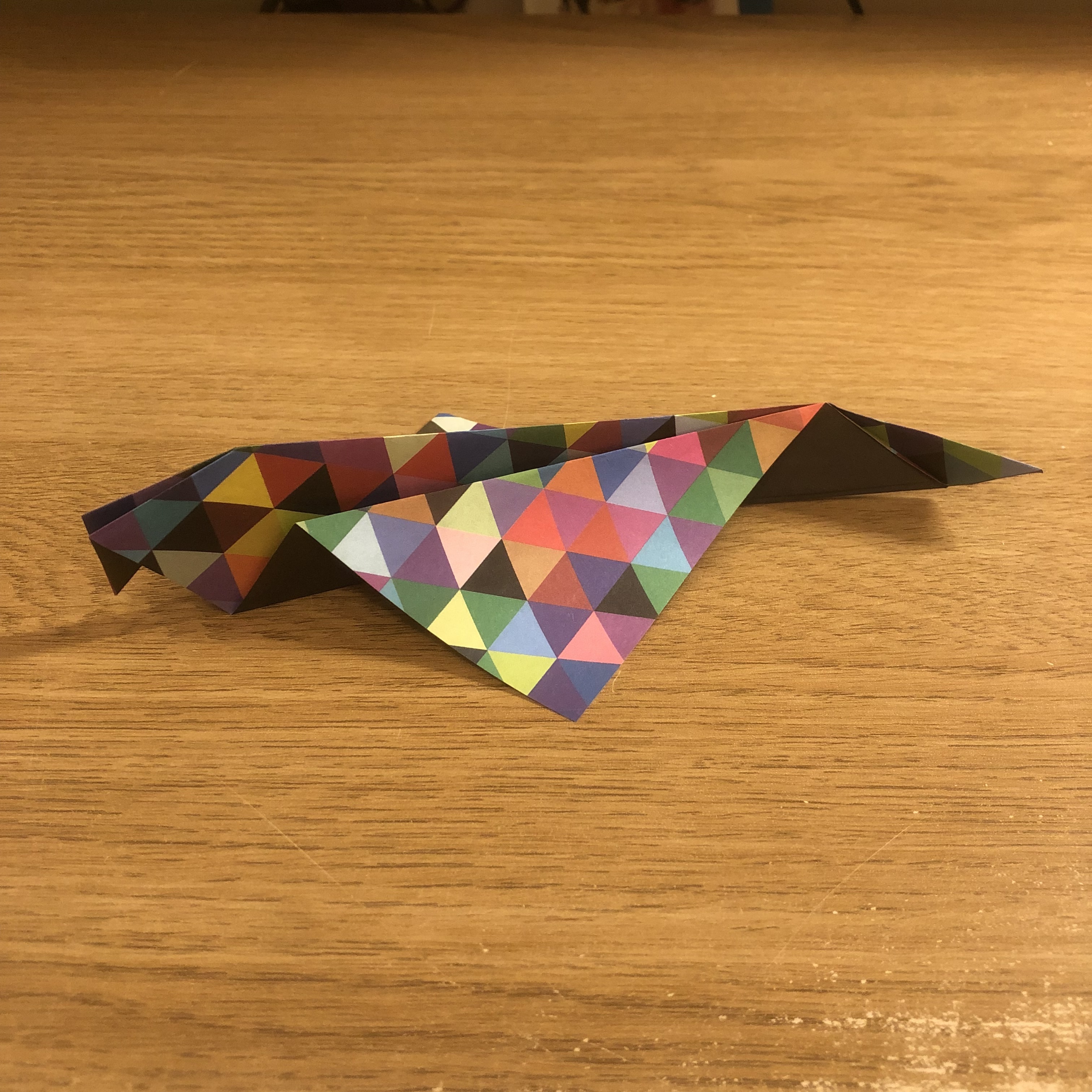 An origami triangle on a wooden table.