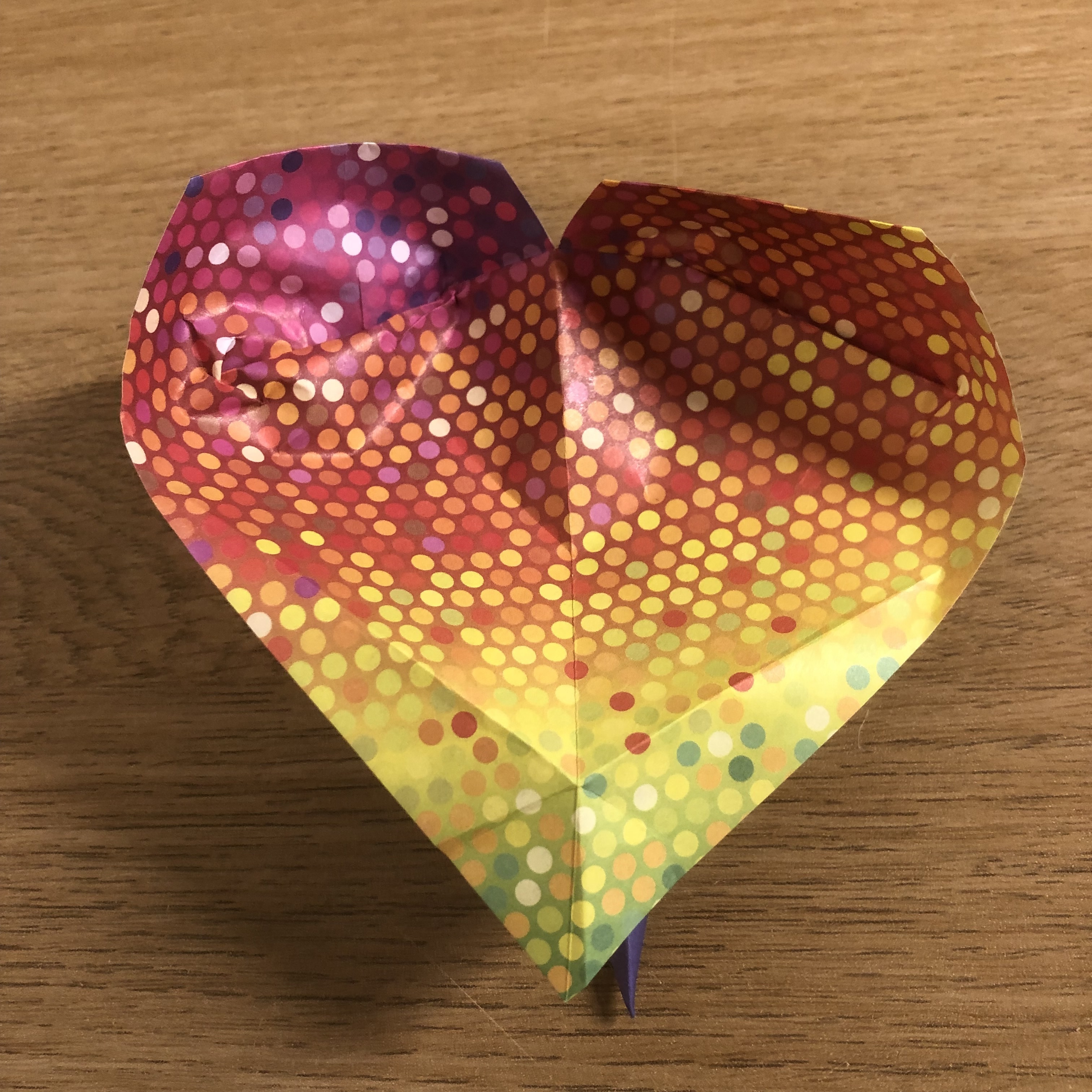 An origami heart on a wooden table.