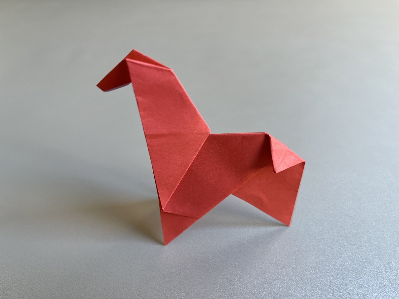 A red origami giraffe sitting on a table.