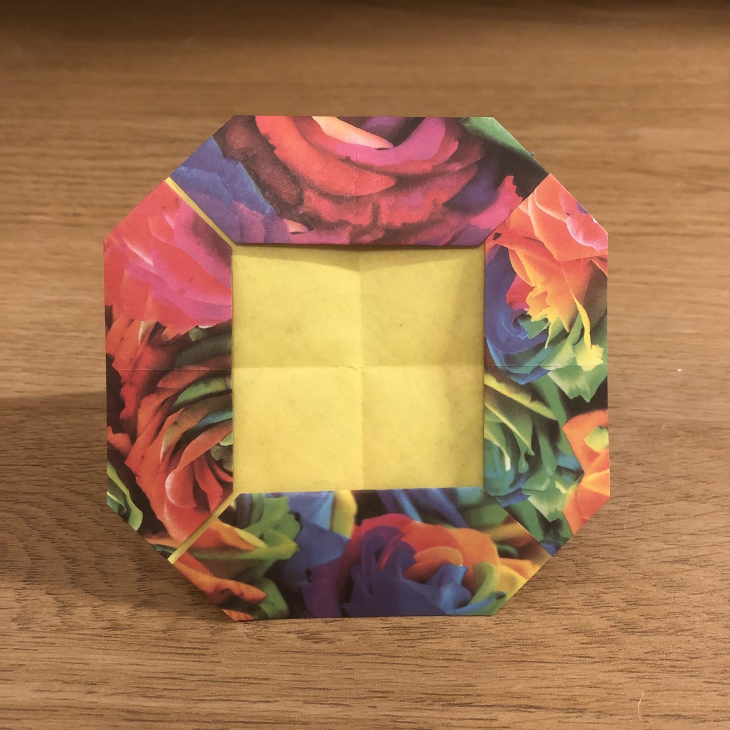 An origami flower frame on top of a wooden table.