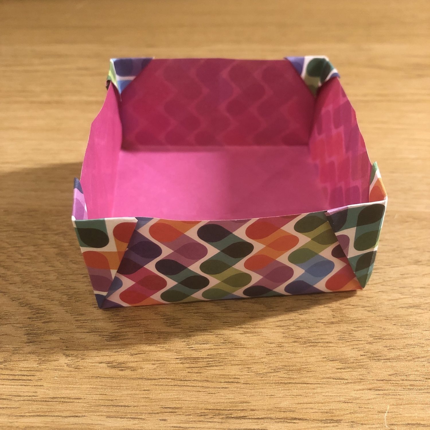 An origami box on top of a wooden table.
