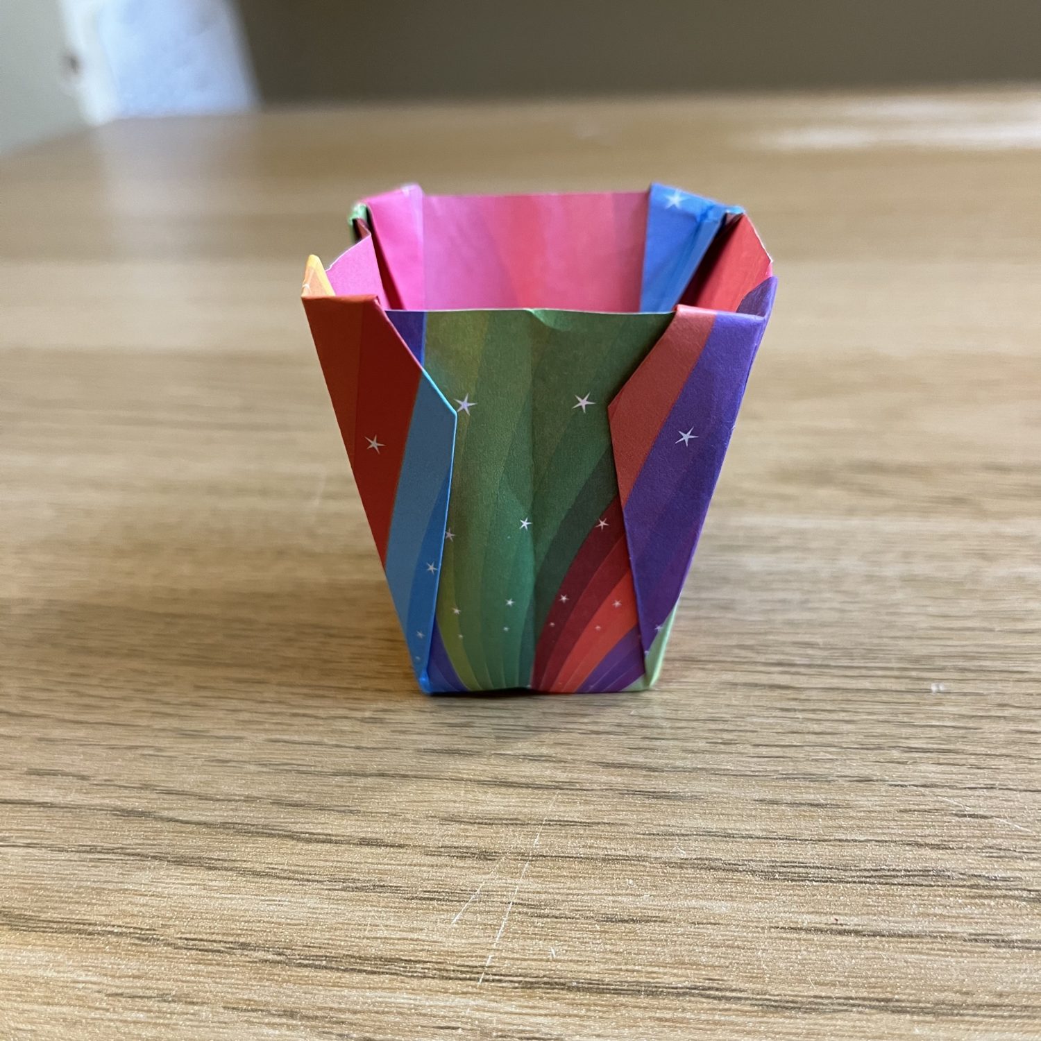 A colorful origami cup sitting on a table.
