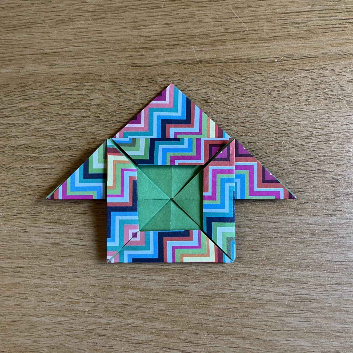 A colorful origami house on a wooden table.