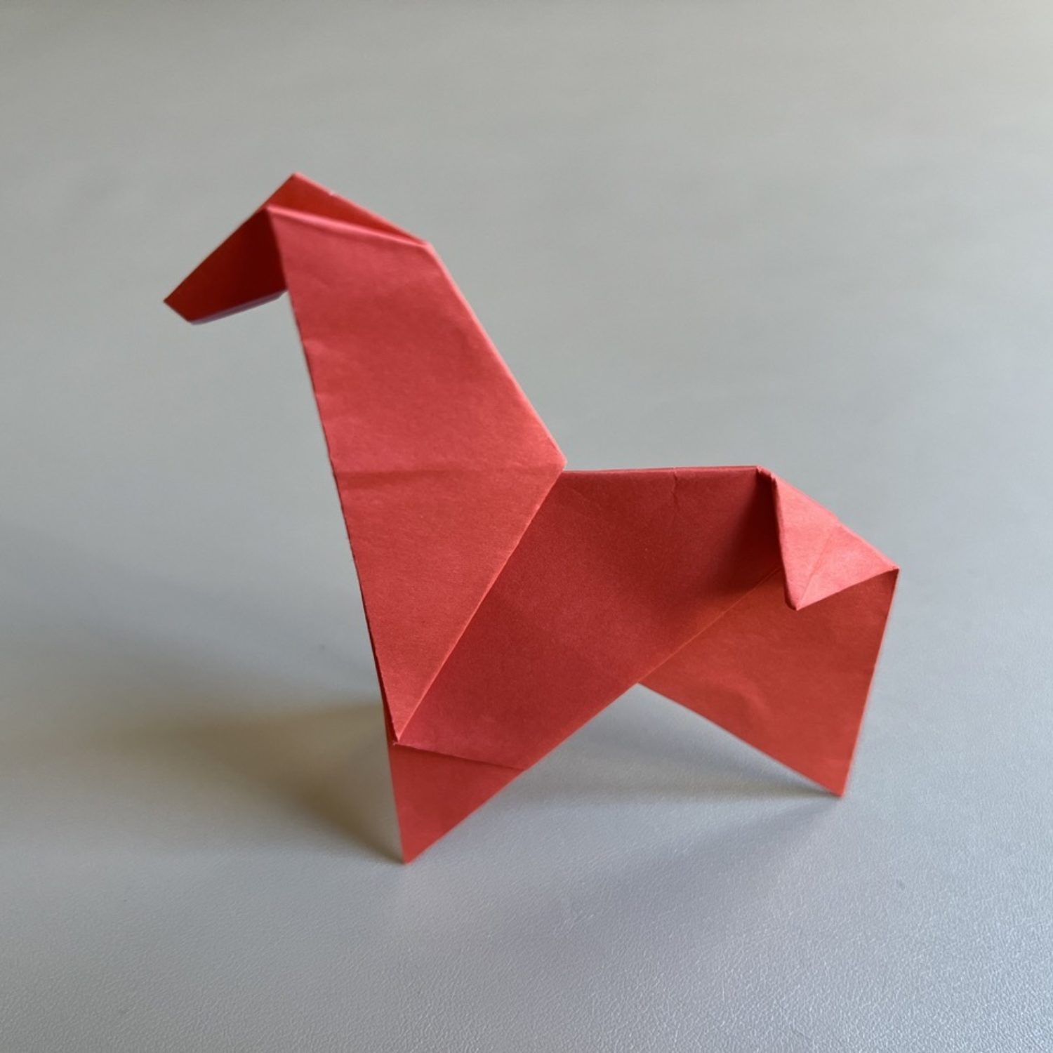 A red origami giraffe sitting on a table.