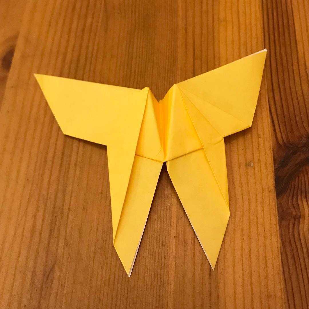 A yellow origami butterfly on a wooden table.
